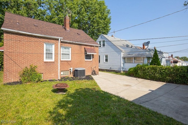 4435 W 58th St, Cleveland, OH 44144 - back of house with brick siding, a chimney, a lawn, a fire pit, and a shingled roof