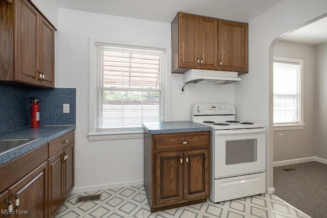 4435 W 58th St, Cleveland, OH 44144 - kitchen with white electric range, custom exhaust hood, dark countertops, arched walkways, and brown cabinetry