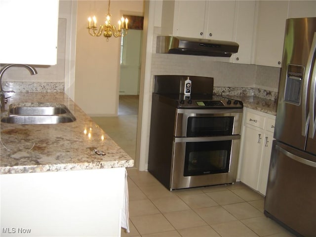 1275 NW Janet Ave, North Canton, OH 44720 - kitchen featuring appliances with stainless steel finishes, under cabinet range hood, white cabinets, a chandelier, and backsplash