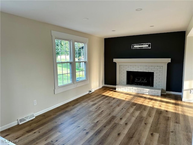832 Meese Rd NE, Louisville, OH 44641 - unfurnished living room featuring wood finished floors and a brick fireplace