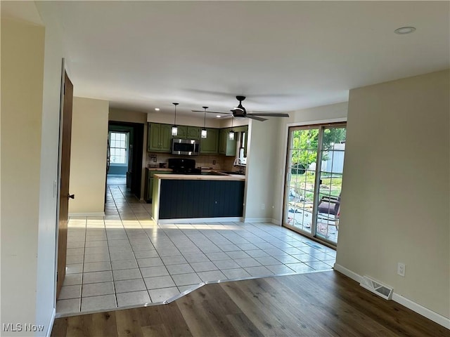 832 Meese Rd NE, Louisville, OH 44641 - kitchen with stainless steel microwave, stove, a ceiling fan, a peninsula, and light tile patterned floors
