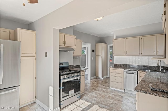 4305 W 49th St, Cleveland, OH 44144 - kitchen featuring appliances with stainless steel finishes, cream cabinetry, under cabinet range hood, and dark stone countertops