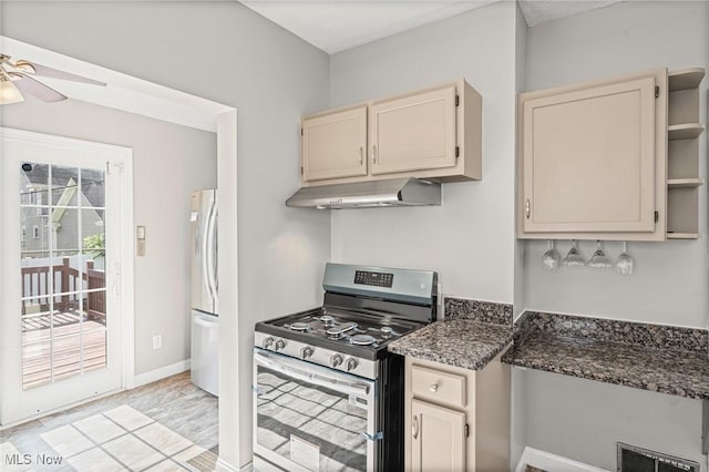 4305 W 49th St, Cleveland, OH 44144 - kitchen with stainless steel range with gas cooktop, under cabinet range hood, freestanding refrigerator, ceiling fan, and cream cabinets