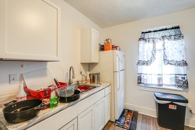 923 Lawton St, Akron, OH 44320 - kitchen featuring wood finished floors, light countertops, a textured ceiling, white cabinetry, and freestanding refrigerator