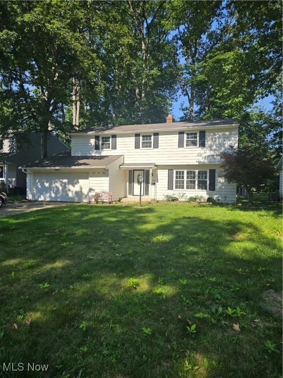 4590 Brendan Ln, North Olmsted, OH 44070 - colonial-style house with a front lawn, an attached garage, and a chimney