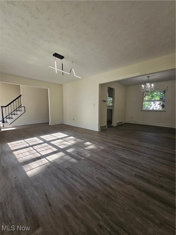 4590 Brendan Ln, North Olmsted, OH 44070 - unfurnished living room with a textured ceiling, a chandelier, wood finished floors, and stairs