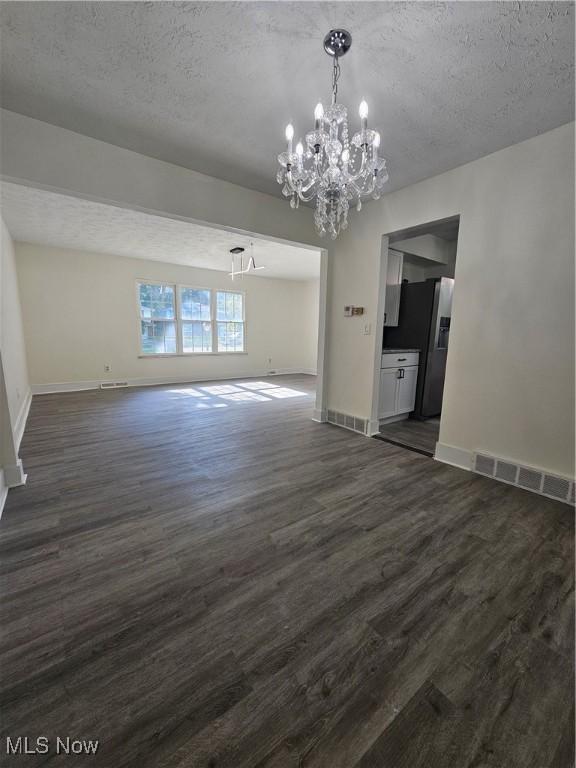 4590 Brendan Ln, North Olmsted, OH 44070 - unfurnished dining area featuring a chandelier, dark wood-style floors, and a textured ceiling