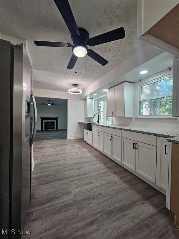 4590 Brendan Ln, North Olmsted, OH 44070 - kitchen with stainless steel refrigerator with ice dispenser, ceiling fan, white cabinetry, dark wood-style flooring, and a textured ceiling