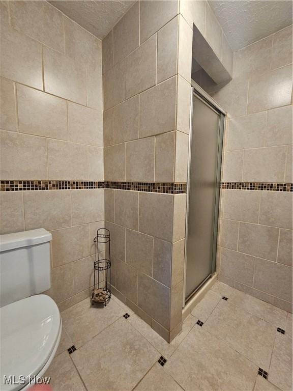 4590 Brendan Ln, North Olmsted, OH 44070 - bathroom with tile walls, a shower stall, tile patterned flooring, and a textured ceiling
