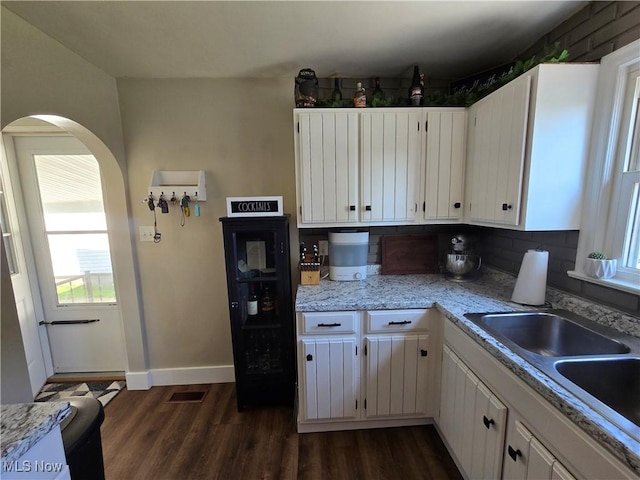 119 E 6th St, Williamstown, WV 26187 - kitchen with arched walkways, dark wood-style floors, tasteful backsplash, and white cabinets