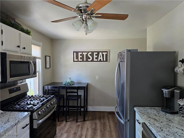 119 E 6th St, Williamstown, WV 26187 - kitchen featuring stainless steel appliances, ceiling fan, wood finished floors, white cabinets, and light stone countertops