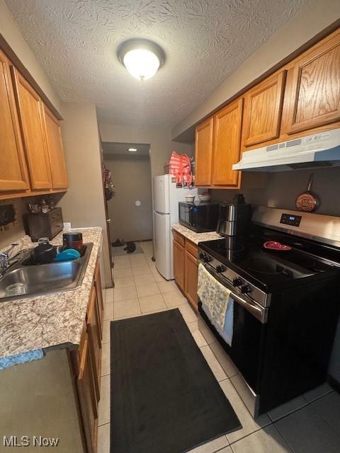 4385 Inner Circle Dr Unit B18, Brunswick, OH 44212 - kitchen featuring stainless steel range with electric stovetop, under cabinet range hood, light tile patterned floors, light countertops, and brown cabinetry