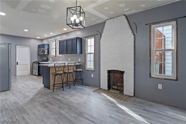 4010 11th Ave, Parkersburg, WV 26101 - kitchen featuring appliances with stainless steel finishes, a breakfast bar, light wood finished floors, a peninsula, and healthy amount of natural light