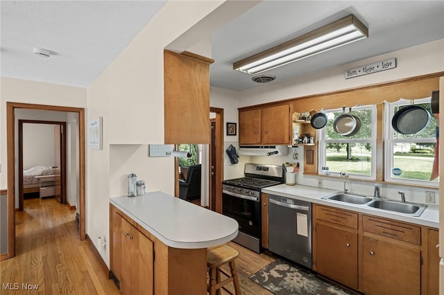 34 Prospect St, Seville, OH 44273 - kitchen with stainless steel appliances, light wood-type flooring, light countertops, a peninsula, and a kitchen bar