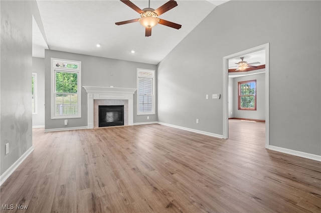 4428 Trail Head Cir NW, Massillon, OH 44647 - unfurnished living room with ceiling fan, plenty of natural light, wood finished floors, a tiled fireplace, and high vaulted ceiling
