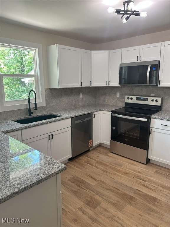 9822 Hooper Rd, Athens, OH 45701 - kitchen with appliances with stainless steel finishes, white cabinets, light wood-style floors, decorative backsplash, and light stone counters