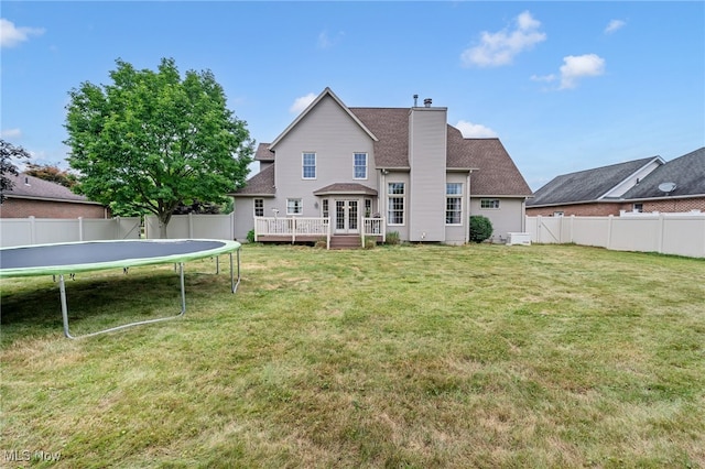 1133 S Azalea Blvd, Barberton, OH 44203 - back of house with a trampoline, a fenced backyard, a wooden deck, a chimney, and roof with shingles