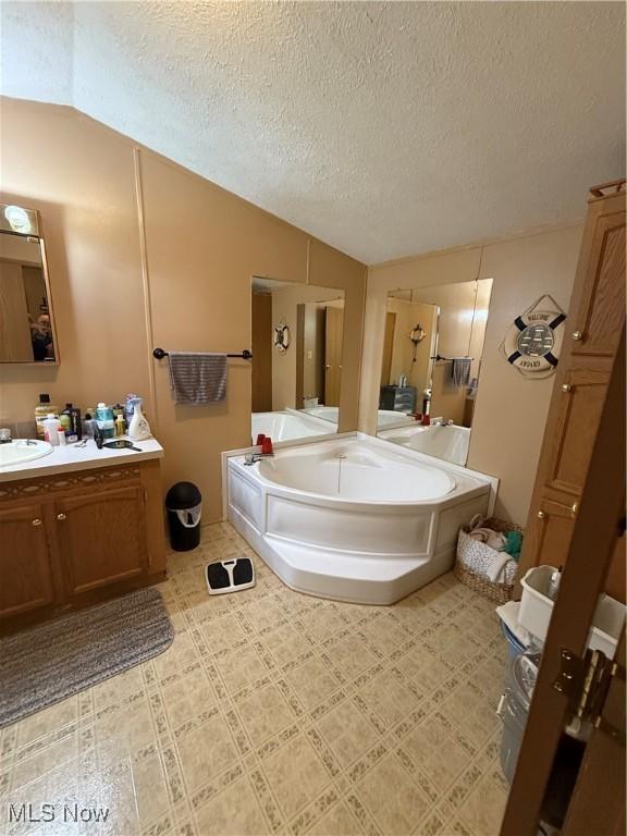 3925 N Ridge E, Ashtabula, OH 44004 - full bathroom featuring a bath, vanity, vaulted ceiling, and a textured ceiling