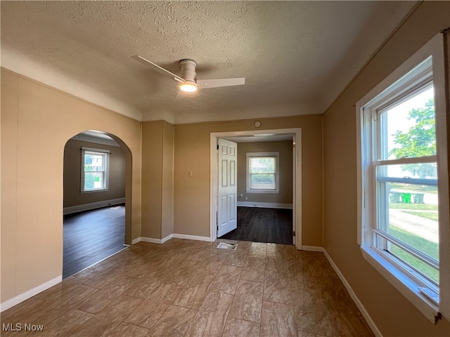 1365 Craneing Rd, Wickliffe, OH 44092 - unfurnished room with plenty of natural light, a textured ceiling, a ceiling fan, arched walkways, and wood finished floors