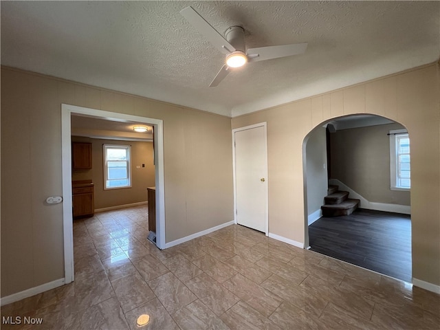 1365 Craneing Rd, Wickliffe, OH 44092 - spare room with arched walkways, a ceiling fan, a textured ceiling, stairs, and ornamental molding