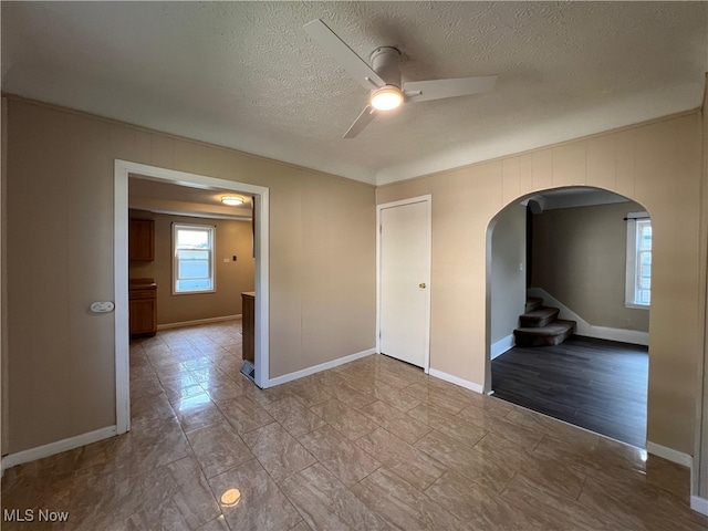 1365 Craneing Rd, Wickliffe, OH 44092 - empty room featuring arched walkways, a ceiling fan, a textured ceiling, and stairway