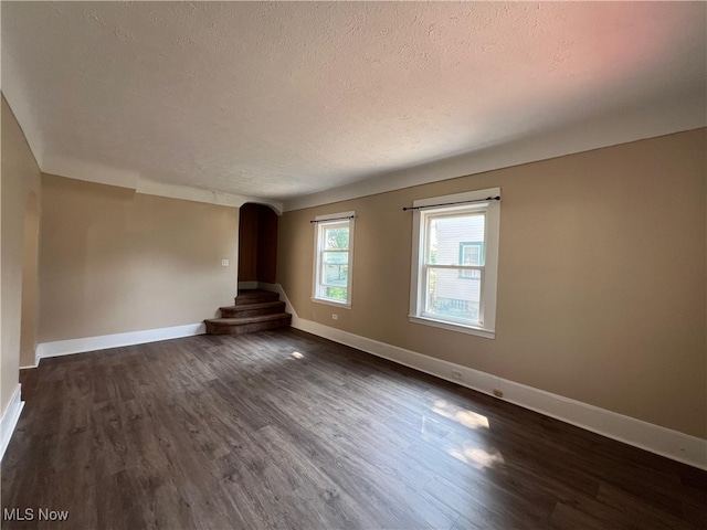 1365 Craneing Rd, Wickliffe, OH 44092 - unfurnished living room with a textured ceiling, dark wood-type flooring, and arched walkways