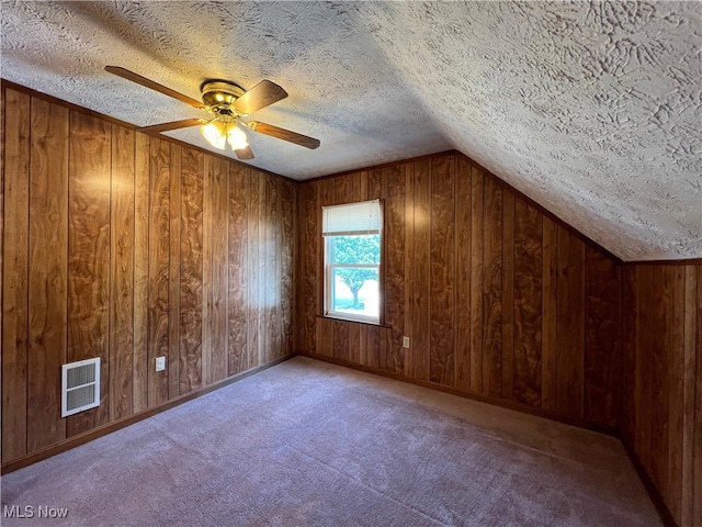 1365 Craneing Rd, Wickliffe, OH 44092 - additional living space featuring a textured ceiling, ceiling fan, vaulted ceiling, wooden walls, and carpet