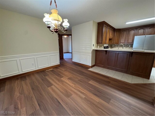 1204 Saint Abigail St SW, Hartville, OH 44632 - kitchen with a chandelier, light countertops, light wood-type flooring, pendant lighting, and a peninsula