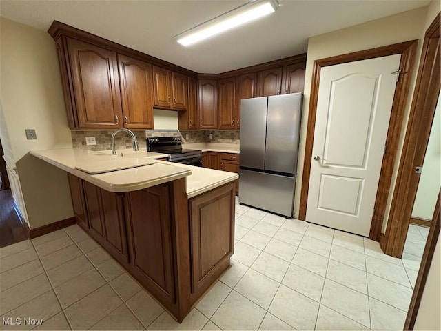 1204 Saint Abigail St SW, Hartville, OH 44632 - kitchen featuring freestanding refrigerator, black range with electric cooktop, a peninsula, light tile patterned flooring, and decorative backsplash