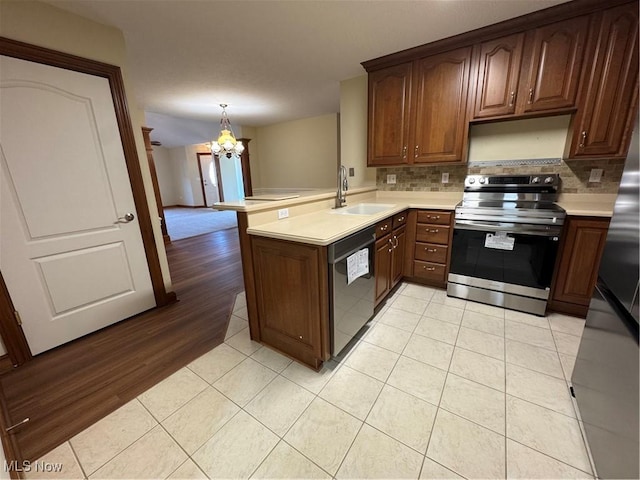 1204 Saint Abigail St SW, Hartville, OH 44632 - kitchen featuring stainless steel appliances, a chandelier, a peninsula, light countertops, and tasteful backsplash