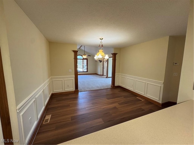 1204 Saint Abigail St SW, Hartville, OH 44632 - unfurnished dining area with a decorative wall, ornate columns, dark wood-style flooring, a chandelier, and a textured ceiling