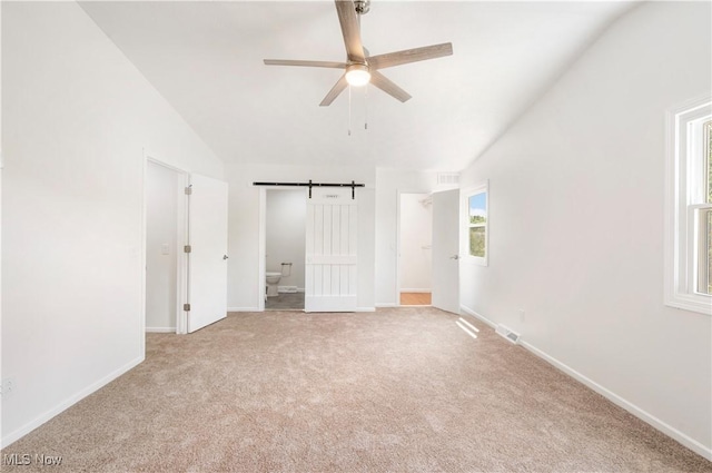 12366 Springwater Ave NW, Uniontown, OH 44685 - unfurnished bedroom featuring carpet, a barn door, ensuite bath, and vaulted ceiling