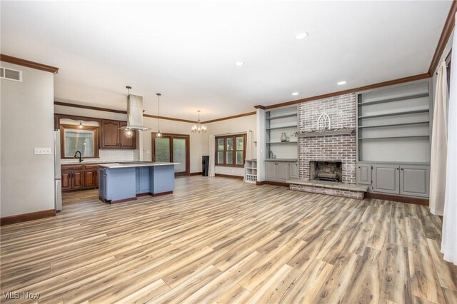 1096 Colegate Dr, Marietta, OH 45750 - unfurnished living room featuring crown molding, light wood finished floors, recessed lighting, a chandelier, and a brick fireplace