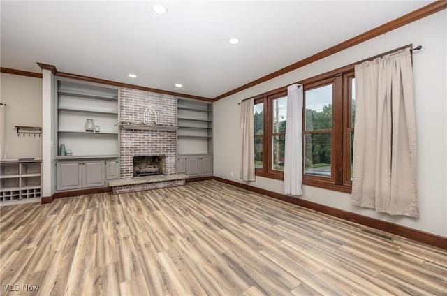 1096 Colegate Dr, Marietta, OH 45750 - unfurnished living room featuring crown molding, light wood-type flooring, recessed lighting, a brick fireplace, and built in shelves