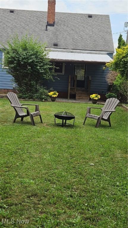 25801 Zeman Ave, Euclid, OH 44132 - back of house featuring an outdoor fire pit, roof with shingles, a lawn, and a chimney