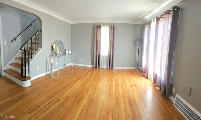 25801 Zeman Ave, Euclid, OH 44132 - unfurnished living room with light wood-style flooring, arched walkways, and stairway
