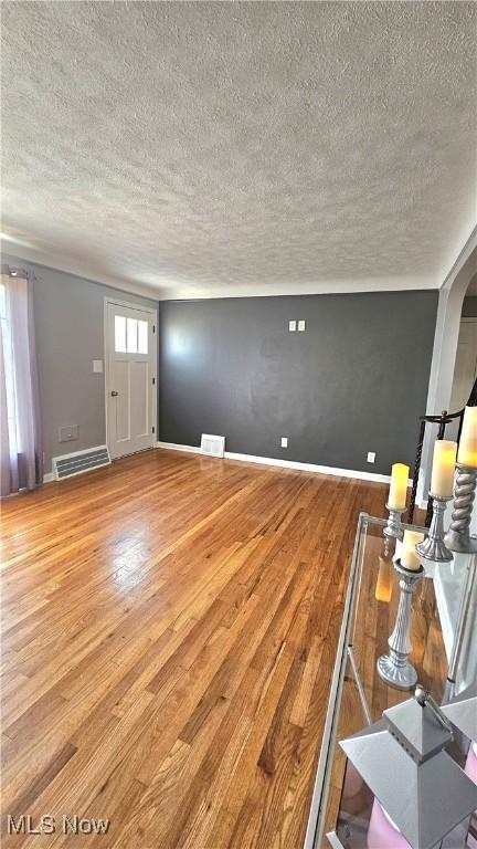 25801 Zeman Ave, Euclid, OH 44132 - unfurnished living room with a textured ceiling, wood finished floors, and arched walkways