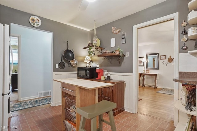 593 Mardon Ave, Akron, OH 44303 - kitchen with black microwave, fridge, wainscoting, open shelves, and ceiling fan
