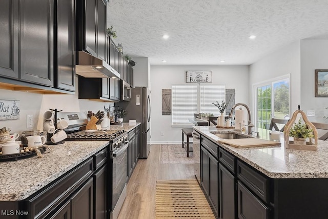 2014 Sugar Maple Dr, Kent, OH 44240 - kitchen with stainless steel appliances, extractor fan, a kitchen island with sink, dark cabinetry, and light wood finished floors