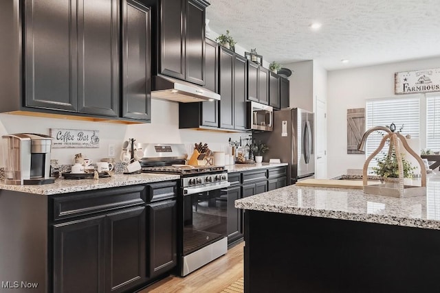2014 Sugar Maple Dr, Kent, OH 44240 - kitchen featuring appliances with stainless steel finishes, under cabinet range hood, dark cabinetry, a textured ceiling, and light wood-style flooring