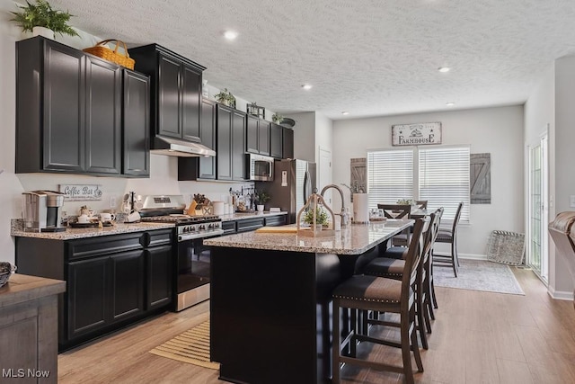 2014 Sugar Maple Dr, Kent, OH 44240 - kitchen with stainless steel appliances, under cabinet range hood, a breakfast bar area, a center island with sink, and dark cabinets