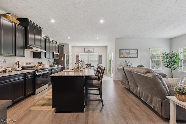 2014 Sugar Maple Dr, Kent, OH 44240 - kitchen featuring appliances with stainless steel finishes, open floor plan, under cabinet range hood, a kitchen breakfast bar, and light stone counters