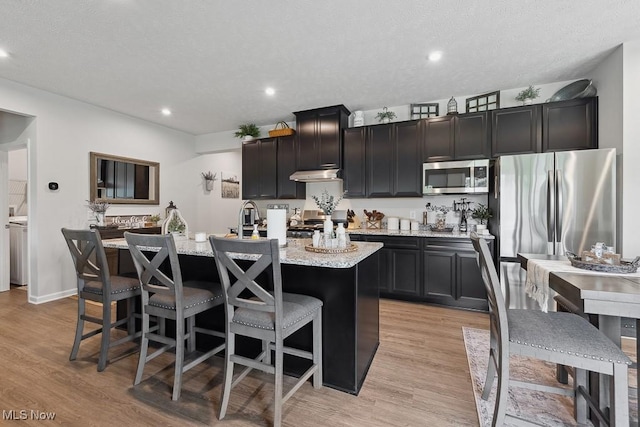 2014 Sugar Maple Dr, Kent, OH 44240 - kitchen with stainless steel appliances, an island with sink, under cabinet range hood, light wood-type flooring, and a kitchen breakfast bar