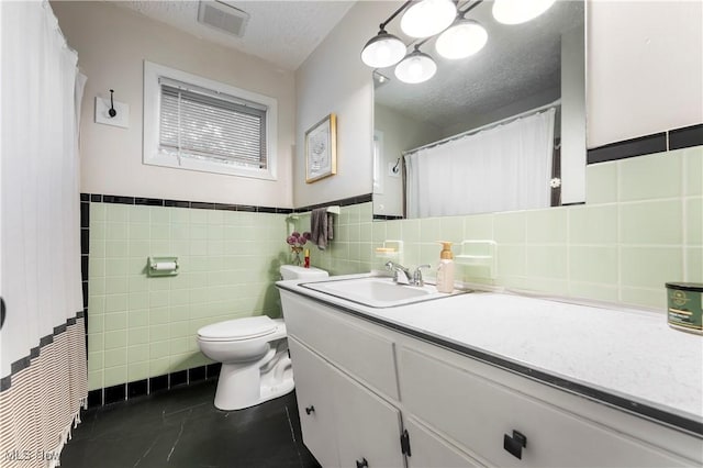 1103 Clinton Ave SE, North Canton, OH 44720 - full bathroom with tile walls, vanity, tile patterned floors, a wainscoted wall, and a textured ceiling