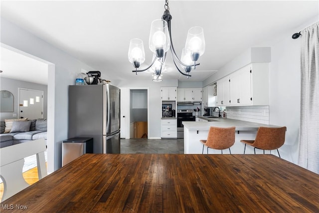 1103 Clinton Ave SE, North Canton, OH 44720 - kitchen featuring appliances with stainless steel finishes, a peninsula, a chandelier, white cabinets, and light countertops