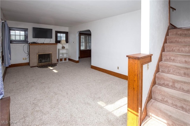 1299 Herberich Ave, Akron, OH 44301 - unfurnished living room with a fireplace, arched walkways, stairway, and carpet