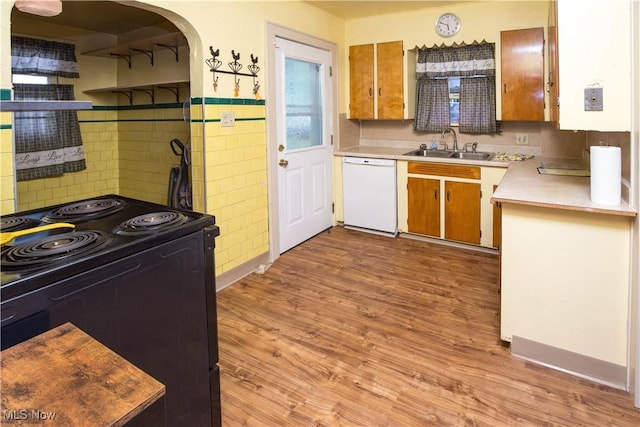 1299 Herberich Ave, Akron, OH 44301 - kitchen with black electric range oven, white dishwasher, arched walkways, light countertops, and light wood-style flooring