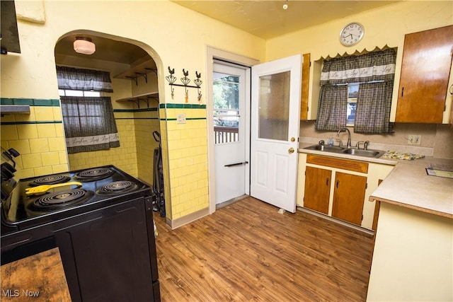 1299 Herberich Ave, Akron, OH 44301 - kitchen featuring black range with electric stovetop, wood finished floors, arched walkways, and light countertops