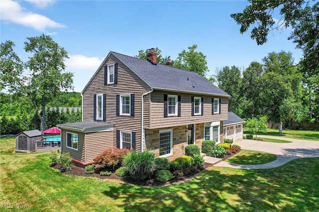 3905 Greenwich Rd, Norton, OH 44203 - view of front of home with driveway, a storage shed, stone siding, a garage, and a chimney