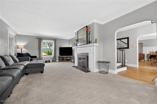 3905 Greenwich Rd, Norton, OH 44203 - carpeted living room with arched walkways, crown molding, stairs, and a fireplace with flush hearth